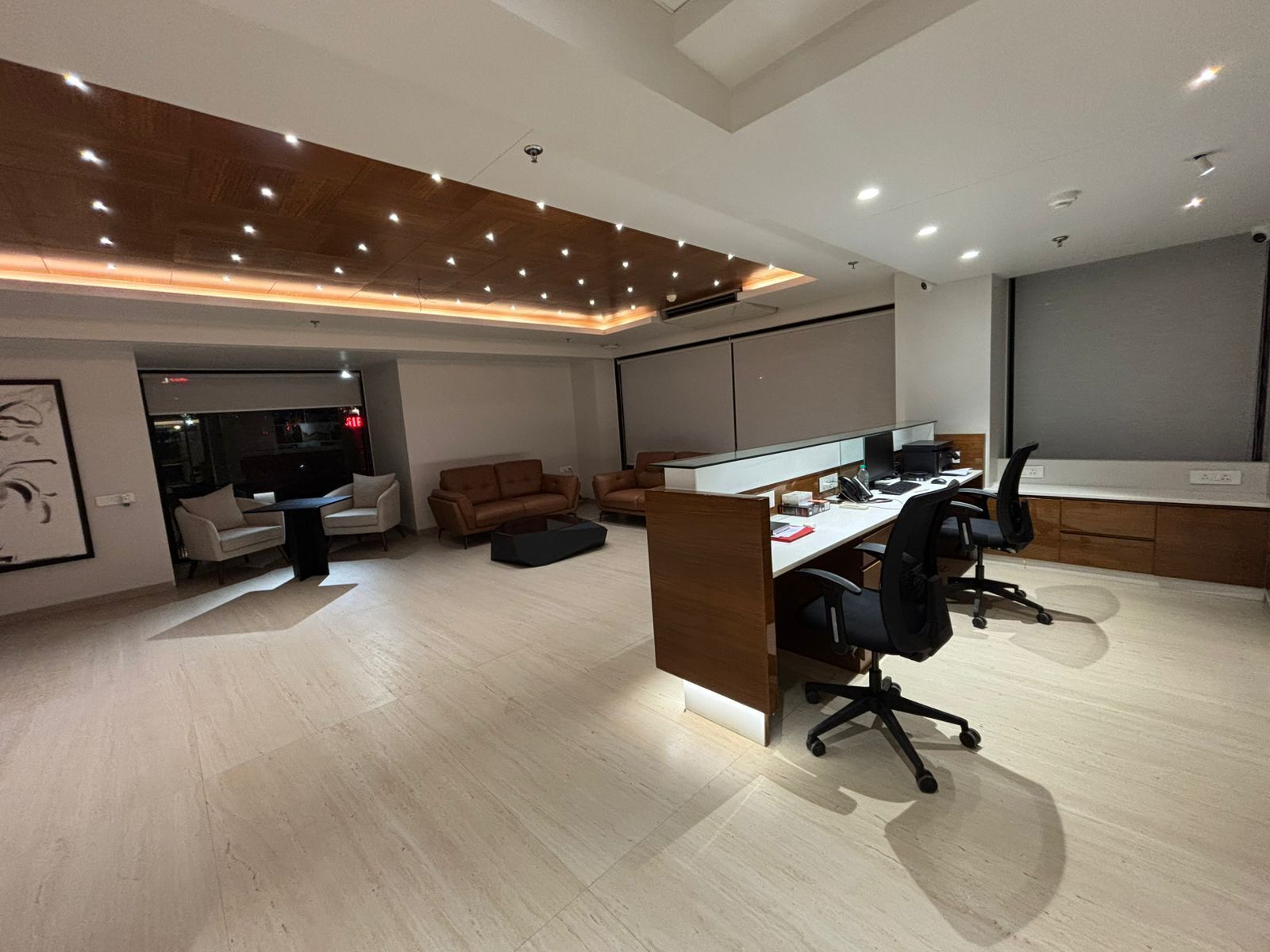 A modern office space with a desk, office chairs, a sofa, and a partition wall.