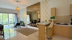 A modern kitchen with a central island, a dining area with a bench, and a large window providing a view of the outdoors. - Ipoh All Suite Resort, Jalan Haven Ipoh (Kinta)