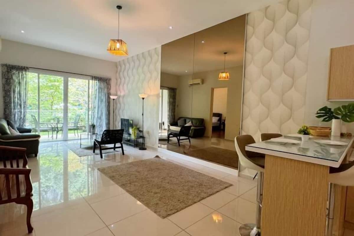 A spacious living area with a large window, a sofa, a coffee table, and a dining area with a glass-top table.