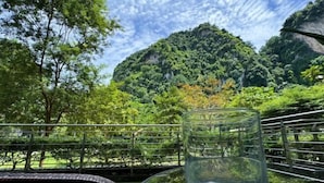 A glass table with a clear glass in the foreground, set against a backdrop of lush greenery and a mountainous landscape. - Ipoh All Suite Resort, Jalan Haven Ipoh (Kinta)
