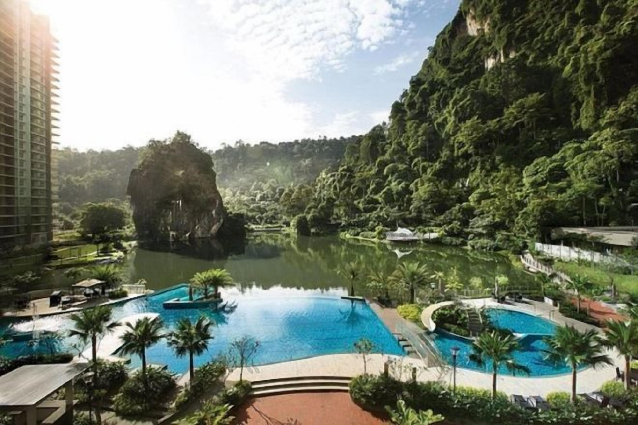 A resort with a large central pool, smaller surrounding pools, and lush greenery.
