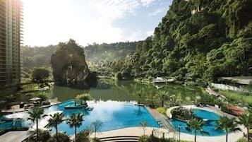 A resort with a large central pool, smaller surrounding pools, and lush greenery.