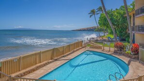 A swimming pool with a wooden deck and a view of the ocean.