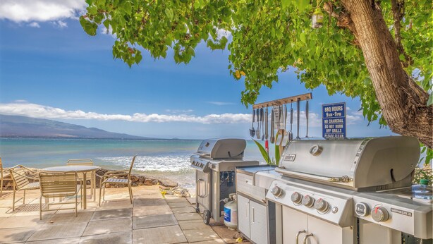 An outdoor patio with a grill and seating area overlooking a beach.