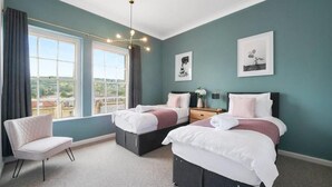 Une chambre avec deux lits, une chaise, une table de chevet et une fenêtre avec des rideaux.