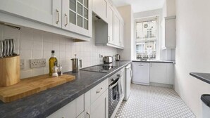 Une cuisine moderne avec des meubles blancs, un plan de travail en granit et un carrelage décoratif.