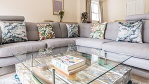 A modern living room with a grey sectional sofa, a glass coffee table, and a framed artwork on the wall. - Spacious Surrey Family Home with Free Parking - Pass the Keys (Addlestone)