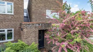 A two-story brick house with a black door and a small front garden. - Spacious Surrey Family Home with Free Parking - Pass the Keys (Addlestone)