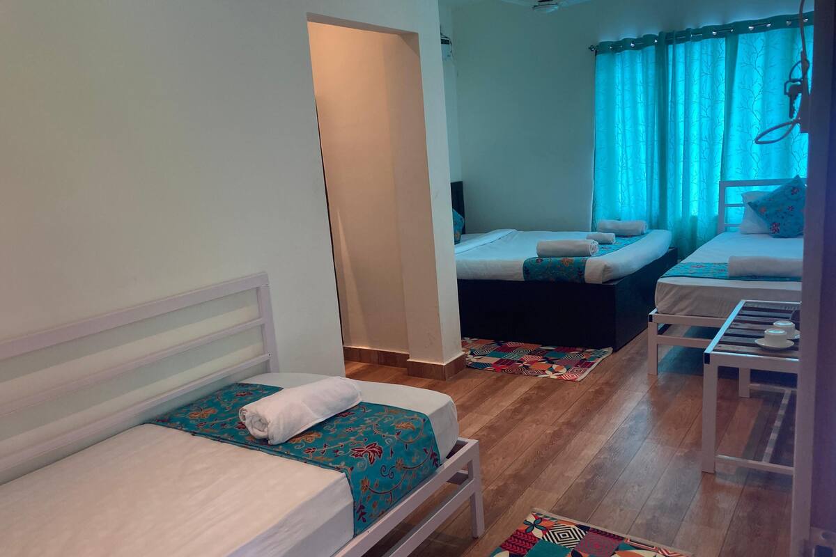 A compact hotel room with two single beds, a small table, and a sofa.