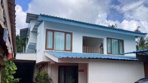 Un edificio de dos pisos con techo azul, un balcón y un letrero que indica un baño.
