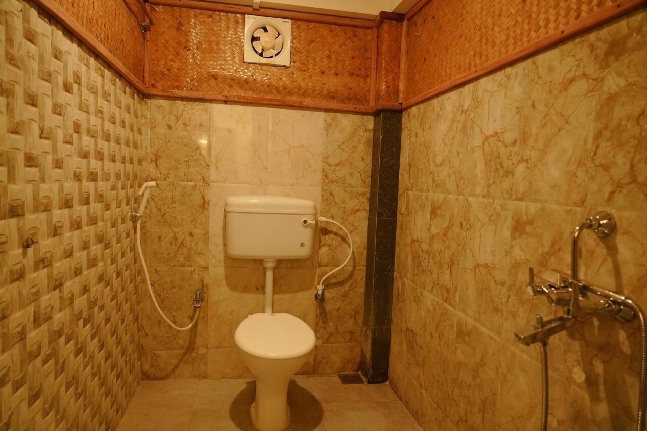 A bathroom with a toilet, a shower, and a fan.