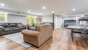 A modern living room with a brown sofa, a grey couch, and a ping pong table. - Beautiful Getaway! 16+ppl and close to Chattanooga! (Ringgold)