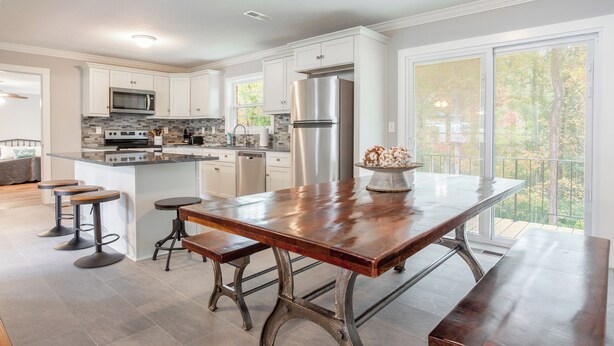 A modern kitchen with white cabinets, stainless steel appliances, and a large island with stools. - Beautiful Getaway! 16+ppl and close to Chattanooga! (Ringgold)