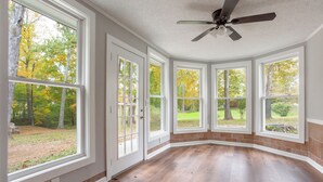 A room with large windows, a ceiling fan, and hardwood flooring. - Beautiful Getaway! 16+ppl and close to Chattanooga! (Ringgold)