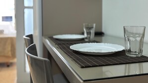 A dining table with two plates and two glasses, a chair, and a wall-mounted TV.