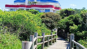 A wooden boardwalk leading to a building with a blue, white, and red facade.