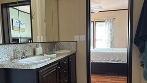 A bathroom with two sinks, a large mirror, and a view into a bedroom with a bed and curtains. - Spacious 3BR Rural Home + Barn Theater One Hour from Dallas, Fort Worth & Waco (Rice)
