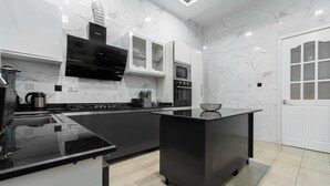 A modern kitchen with black countertops, white cabinets, and a built-in oven.