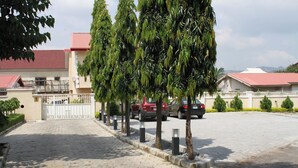 A paved driveway leading to a gated entrance with parked cars. - Top-Notch Suites and Apartment (Abuja)