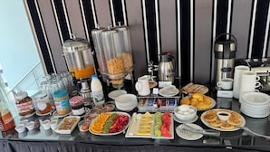 A breakfast buffet with various food items, beverages, and condiments.