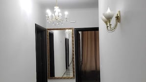 A hallway with a large mirror, a chandelier, and a wall-mounted light fixture.