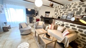 A living room with a stone wall, a fireplace, a television, and a sofa.