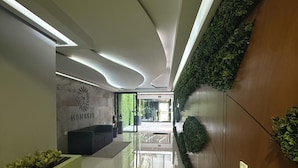 A modern reception area with a logo, a reception desk, and a green planter.