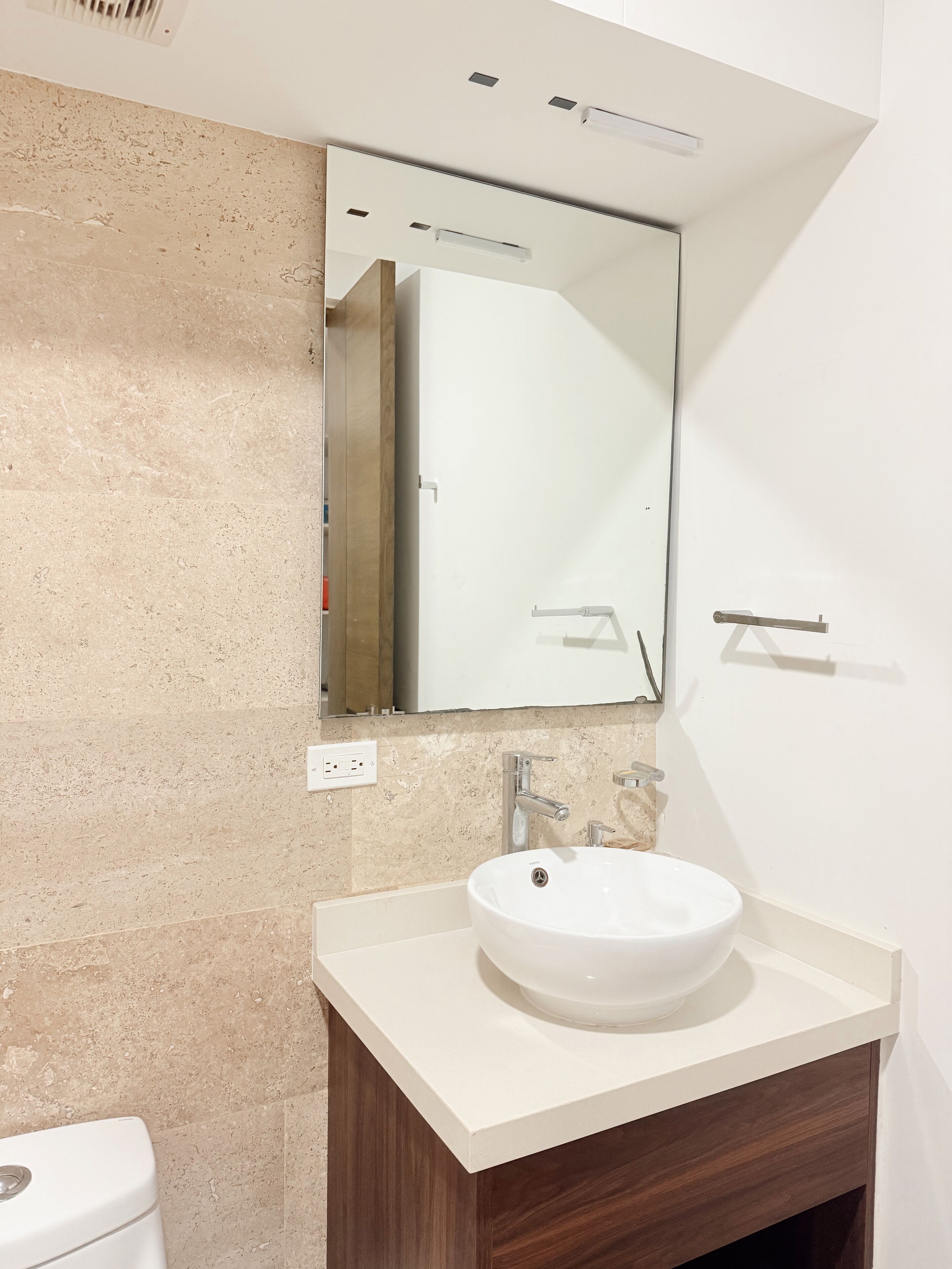 Une salle de bain moderne avec un lavabo blanc, un miroir et un meuble-lavabo en bois.