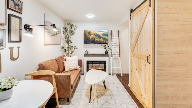 Een knusse woonkamer met een open haard, een bank, een salontafel en een schuifdeur in boerderijstijl.