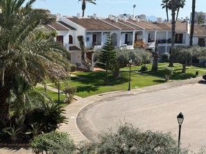 A residential area with white buildings, a curved road, and palm trees.