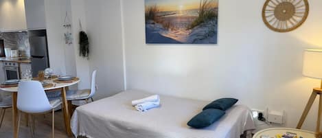 Una camera da letto moderna con un letto, un tavolo da pranzo e angolo cottura.
