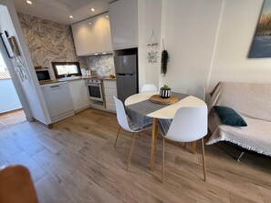 A modern kitchen with white cabinets, a built-in oven, and a stainless steel refrigerator.