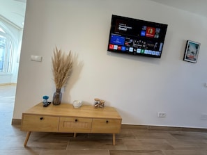 Un salon moderne avec un téléviseur à écran plat fixé au mur, diffusant différentes chaînes.