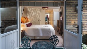 A bedroom with a bed, pillows, and a nightstand. There is a window and a door leading to another room. - Countryside Escape for Friends and Family (Haslemere)