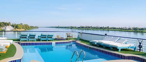 Una piscina al aire libre, sombrillas, tumbonas