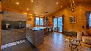 A wooden cabin interior with a kitchen, dining area, and seating space. - Chalet Chanterelle - Cosy and mountainy (Haute-Nendaz)