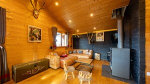 A cozy log cabin interior with a wooden ceiling, a sofa set, a fireplace, and a rustic decor including antler chairs. - Chalet Chanterelle - Cosy and mountainy (Haute-Nendaz)