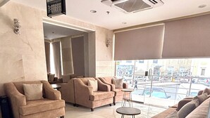 A spacious living area with a large sofa set, a coffee table, and a view of the street through large windows. - Alabraj Hafawa Hotel Company (Makkah)