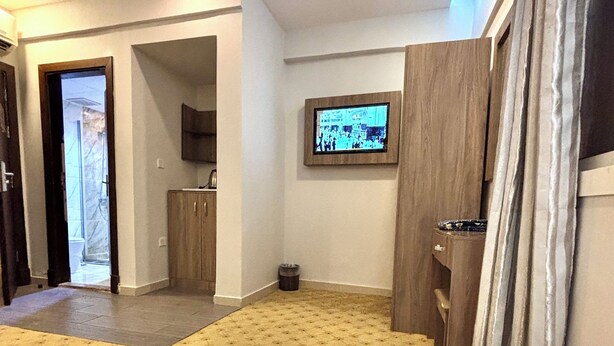 A hotel room with a bed, a television mounted on the wall, a wooden cabinet, and a small trash bin. - Alabraj Hafawa Hotel Company (Makkah)