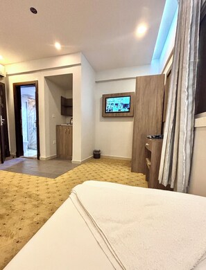 A hotel room with a bed, a television mounted on the wall, a wooden cabinet, and a small trash bin. - Alabraj Hafawa Hotel Company (Makkah)
