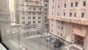 A view from a window overlooking a parking lot with several cars, a building with the sign "DAR LALARI HOTEL" and a person walking on the sidewalk. - Alabraj Hafawa Hotel Company (Makkah)