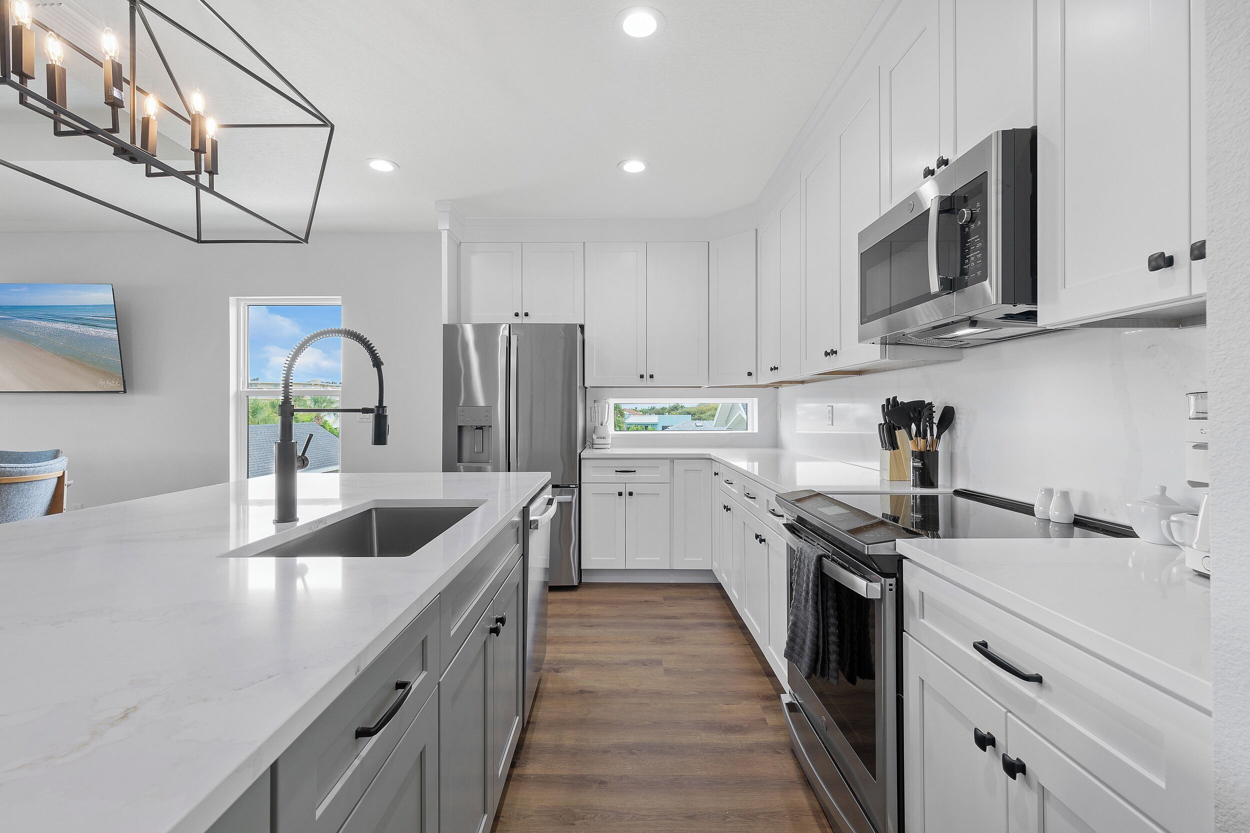A modern kitchen with white cabinetry, stainless steel appliances, and a large window providing a view of the outdoors.