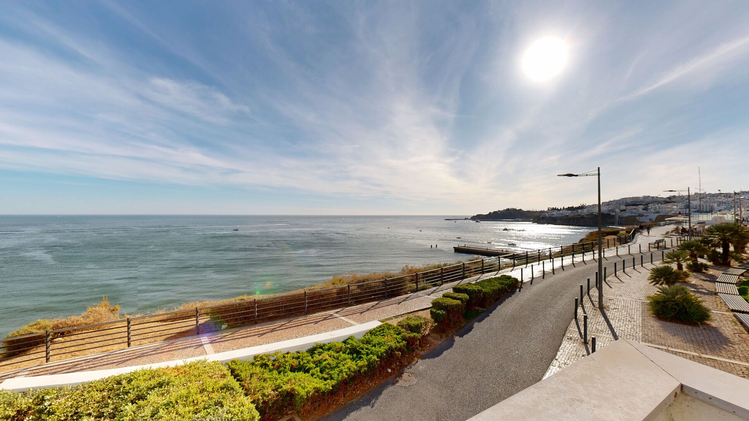 Une promenade en bord de mer offrant une vue sur l’océan, un sentier piétonnier et une ville située au loin.