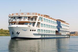 Un gran barco crucero fluvial de varias cubiertas con balcones y ventanas.