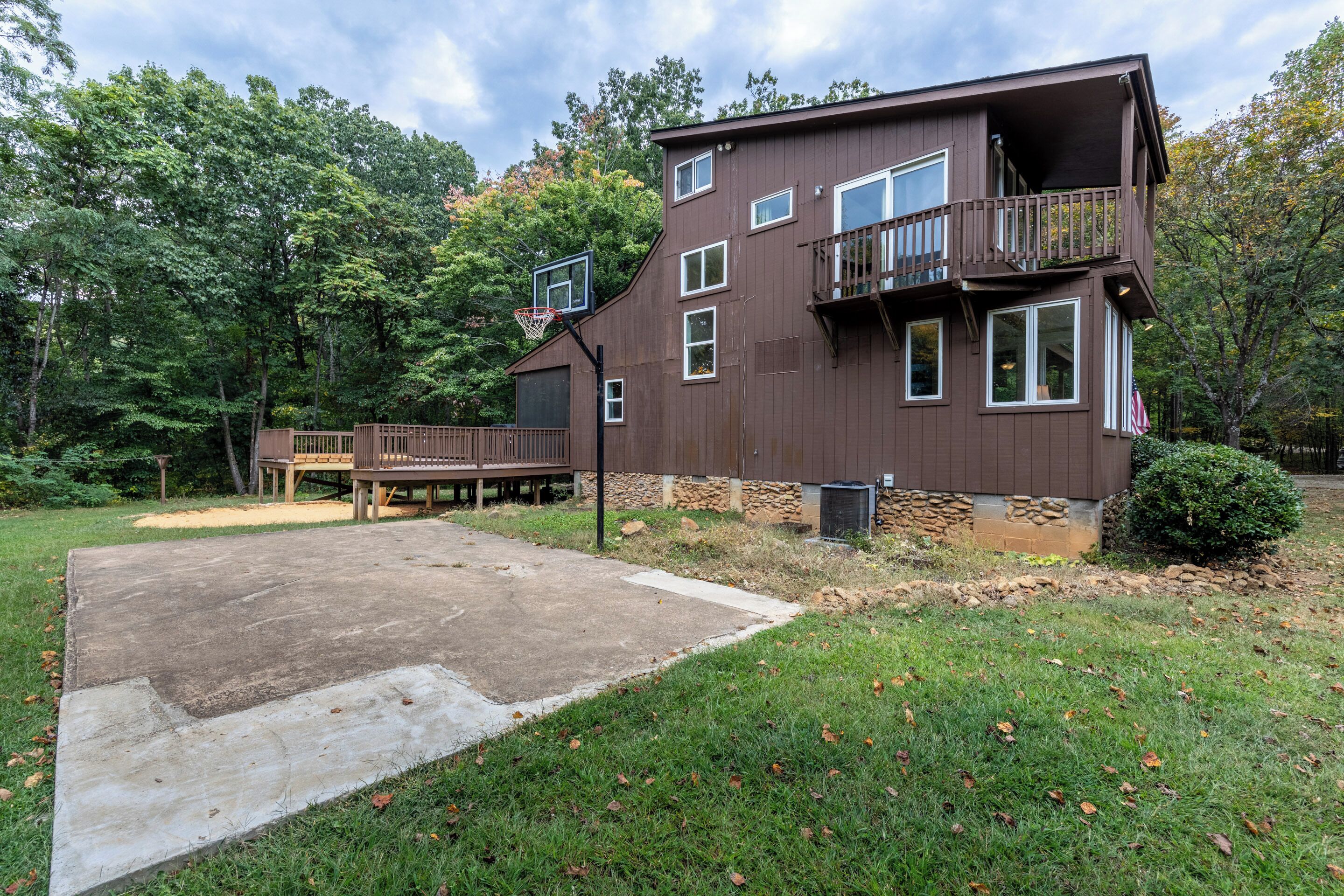 A two-story house with a balcony, a basketball hoop, and a deck.