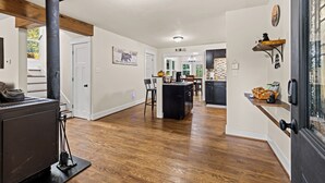 A spacious kitchen with a central island, wooden flooring, and a black stove.