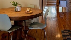 A wooden dining table with chairs, a potted plant, and a plate of pastries. - Wyatt s Saloon Guest House 2 (Baltimore)