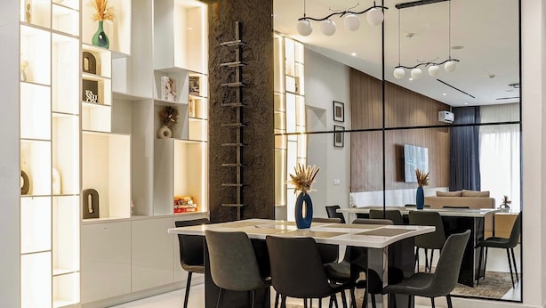 A modern dining area with a white table, black chairs, and a decorative vase.