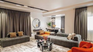 A modern living room with grey sofas, a coffee table, and a bright orange chair.