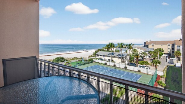 Ein Balkon mit Blick auf einen Strand, Tennisplätze und Wohnhäuser.